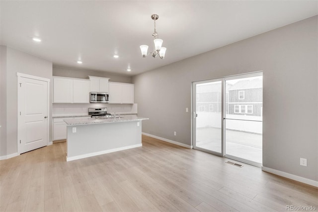 kitchen featuring white cabinets, pendant lighting, stainless steel appliances, and light hardwood / wood-style floors