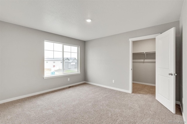 unfurnished bedroom with a walk in closet, carpet floors, and a closet