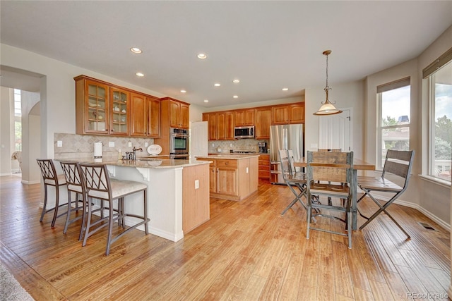 4864 Harness Ct, Parker, CO 80134 - kitchen with stainless steel appliances, a peninsula, light wood-type flooring, decorative backsplash, and recessed lighting