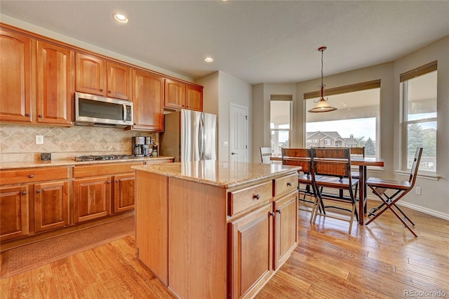 4864 Harness Ct, Parker, CO 80134 - kitchen featuring stainless steel appliances, light stone countertops, light wood-style floors, backsplash, and hanging light fixtures