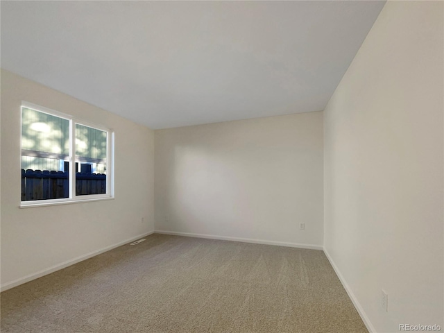 carpeted spare room with visible vents and baseboards