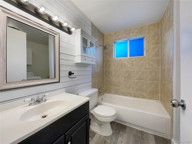 bathroom with toilet, wood finished floors, wooden walls, bathtub / shower combination, and vanity