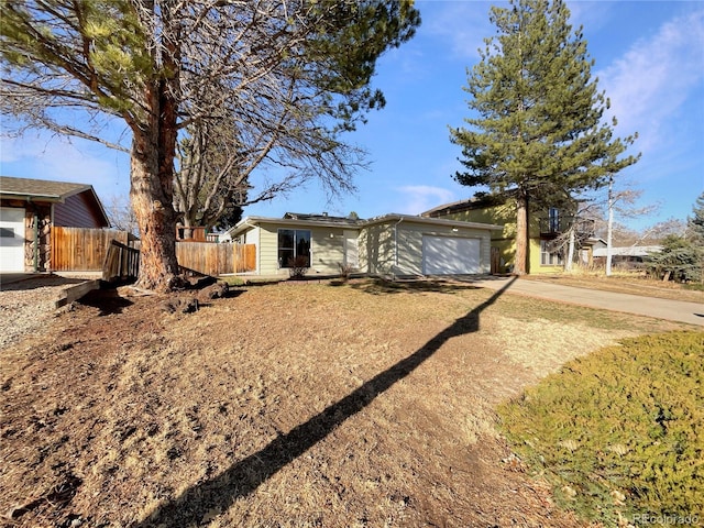 view of front of house with solar panels, an attached garage, fence, and driveway