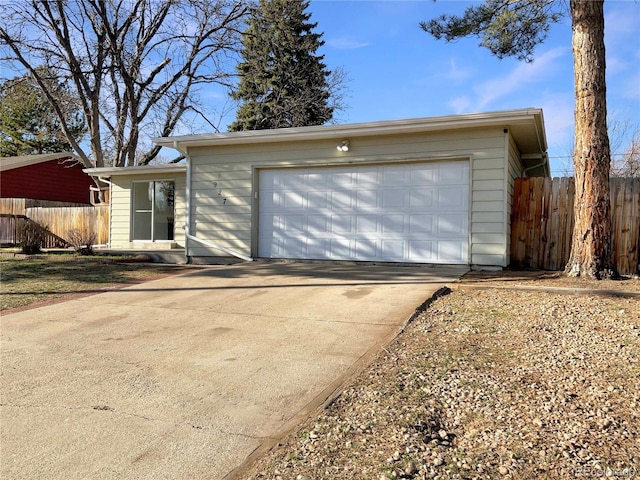 garage with concrete driveway and fence