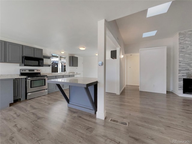 kitchen featuring stainless steel electric stove, visible vents, gray cabinetry, and black microwave