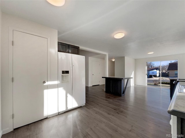 interior space featuring open floor plan, white fridge with ice dispenser, wood finished floors, and a kitchen island