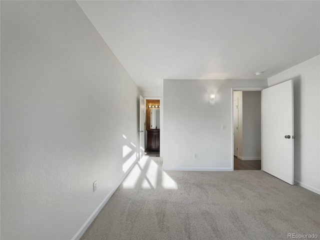 unfurnished bedroom featuring carpet flooring, ensuite bathroom, and baseboards