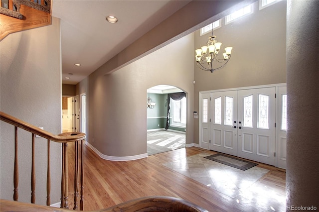 entrance foyer with an inviting chandelier, light hardwood / wood-style floors, and a high ceiling