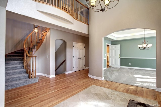 interior space featuring a notable chandelier, hardwood / wood-style flooring, a raised ceiling, and a high ceiling