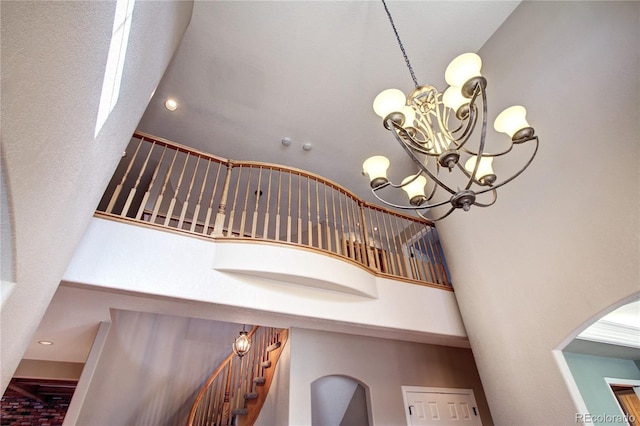 stairs featuring a high ceiling and an inviting chandelier