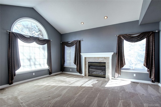 unfurnished living room with vaulted ceiling, light colored carpet, and a high end fireplace