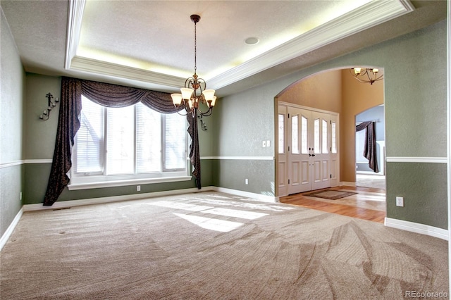 unfurnished room with an inviting chandelier, crown molding, light colored carpet, and a raised ceiling