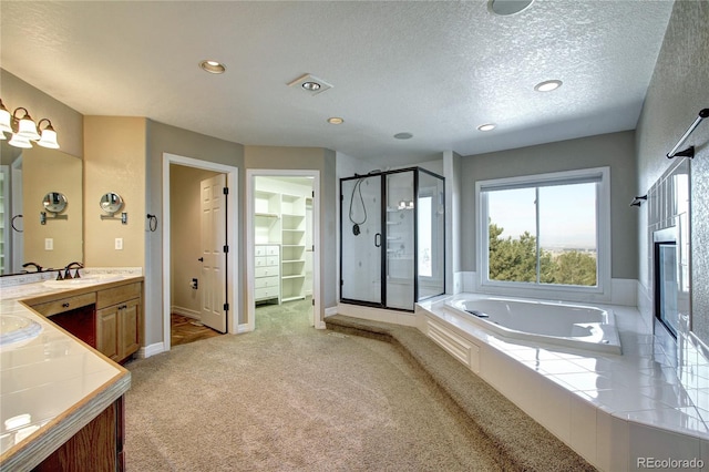 bathroom featuring independent shower and bath, vanity, and a textured ceiling