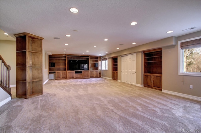 unfurnished living room with light colored carpet and a textured ceiling