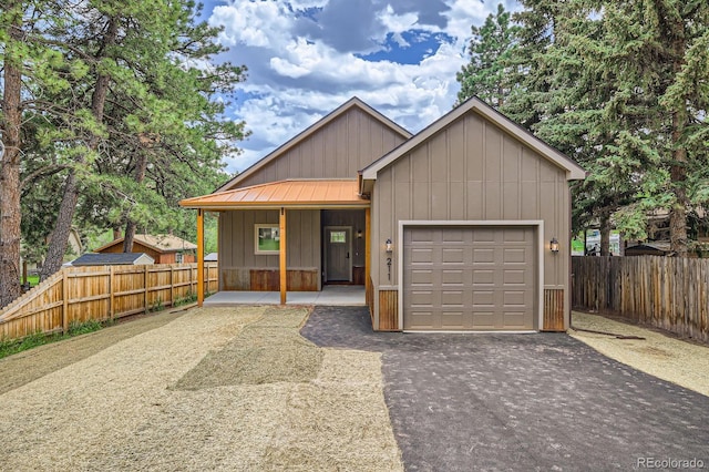 211 E Pikes Peak Ave, Woodland Park, CO 80863 - view of front of home with board and batten siding, driveway, a garage, a porch, and a metal roof
