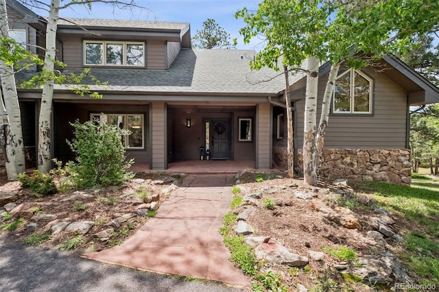 1570 Blakcomb Ct, Evergreen, CO 80439 - view of front facade with a porch, roof with shingles, and stone siding