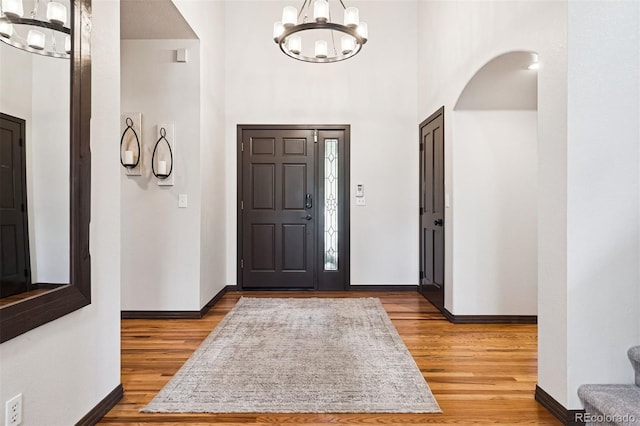 1570 Blakcomb Ct, Evergreen, CO 80439 - foyer with a chandelier, light wood-type flooring, arched walkways, baseboards, and a high ceiling
