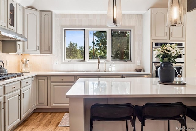 1570 Blakcomb Ct, Evergreen, CO 80439 - kitchen featuring stainless steel appliances, a sink, a kitchen bar, light countertops, and under cabinet range hood