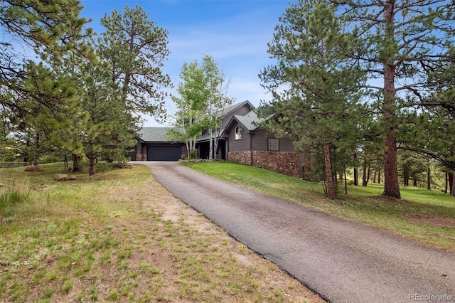 1570 Blakcomb Ct, Evergreen, CO 80439 - obstructed view of property featuring stone siding, driveway, an attached garage, and a front yard