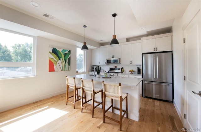 kitchen with appliances with stainless steel finishes, a kitchen breakfast bar, baseboards, and visible vents