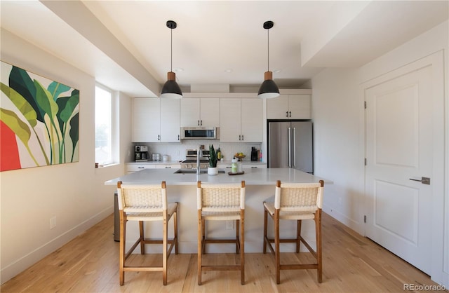 kitchen with an island with sink, light countertops, a kitchen breakfast bar, and stainless steel appliances
