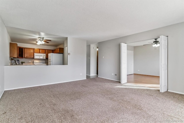 unfurnished living room featuring carpet flooring, a ceiling fan, and baseboards