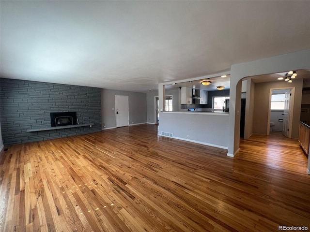 unfurnished living room with a fireplace, a notable chandelier, and hardwood / wood-style flooring