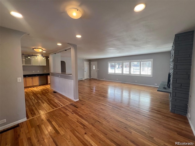 unfurnished living room with a stone fireplace and hardwood / wood-style floors