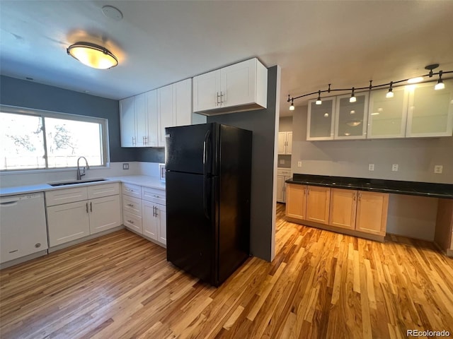 kitchen featuring dishwasher, black refrigerator, sink, light hardwood / wood-style floors, and white cabinetry