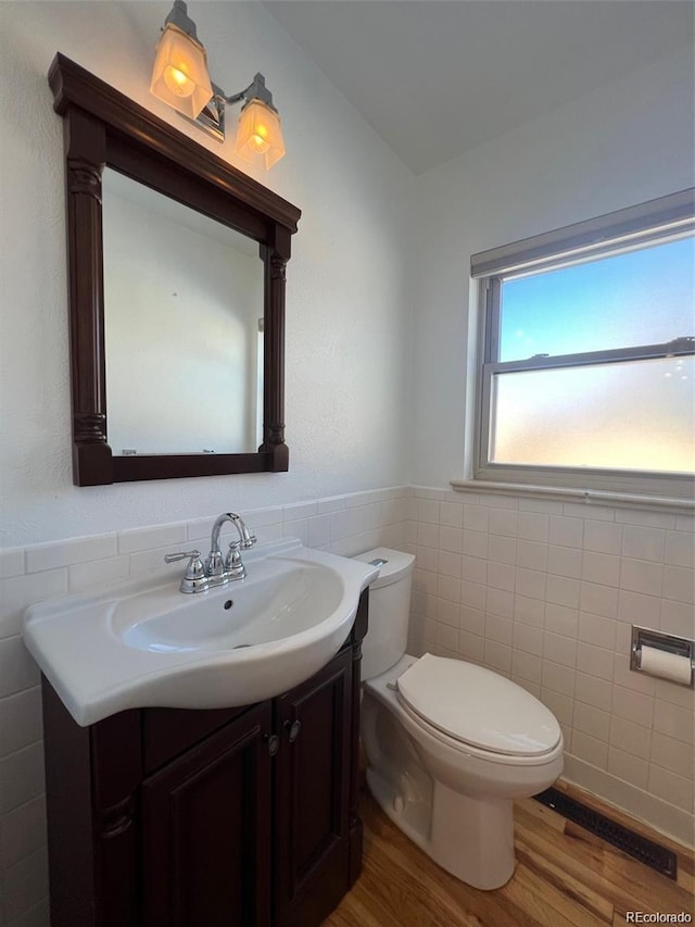 bathroom with vanity, wood-type flooring, tile walls, and toilet