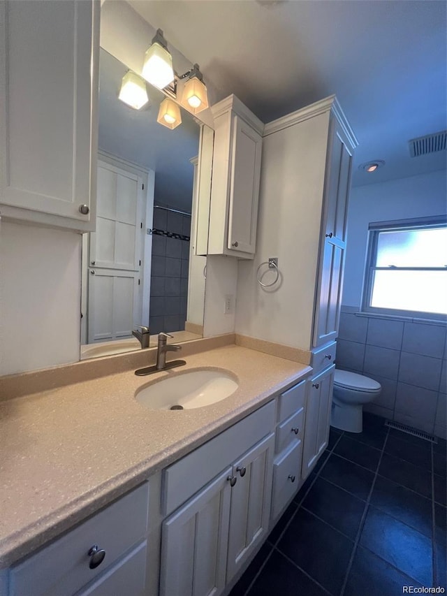 bathroom with tile patterned floors, vanity, tile walls, and toilet