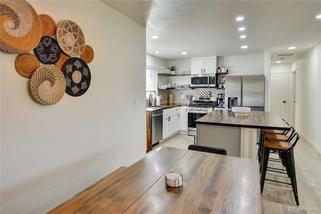 kitchen featuring sink, white cabinetry, appliances with stainless steel finishes, a center island, and a breakfast bar area