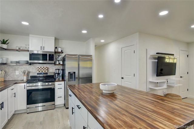 kitchen with appliances with stainless steel finishes, wood counters, light hardwood / wood-style flooring, and white cabinets