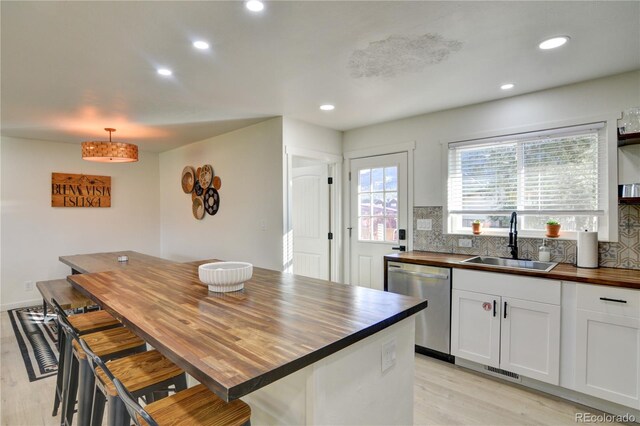 kitchen featuring decorative backsplash, sink, wooden counters, and stainless steel dishwasher