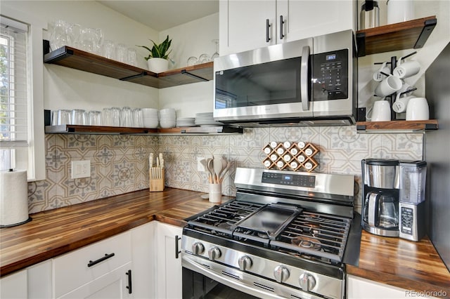 kitchen featuring butcher block countertops, decorative backsplash, stainless steel appliances, and white cabinets