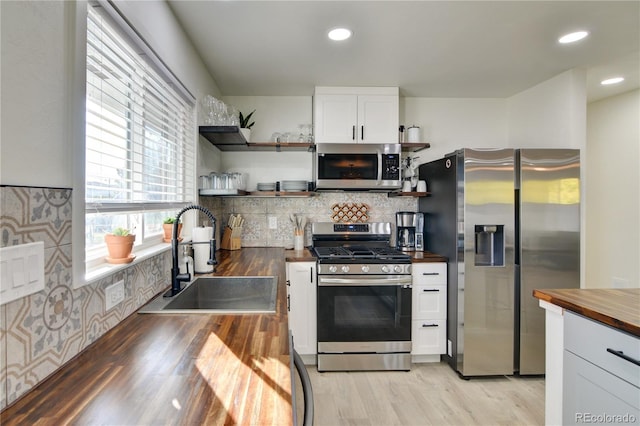 kitchen featuring sink, light hardwood / wood-style flooring, white cabinetry, stainless steel appliances, and wood counters