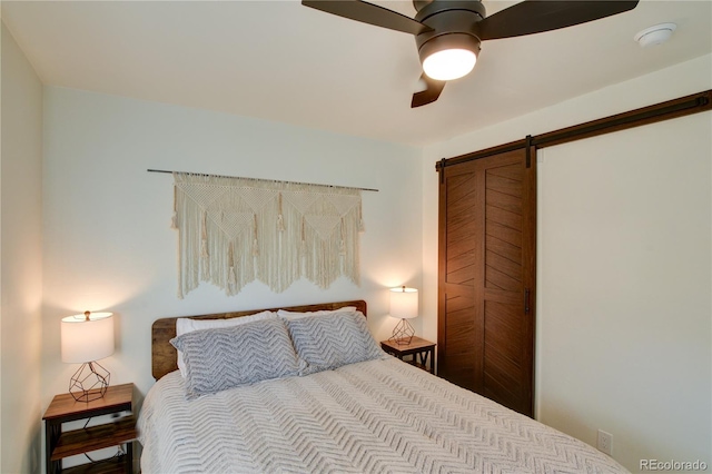 bedroom featuring ceiling fan and a barn door