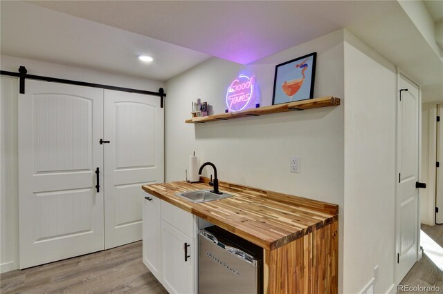 kitchen with white cabinets, sink, a barn door, and wood counters