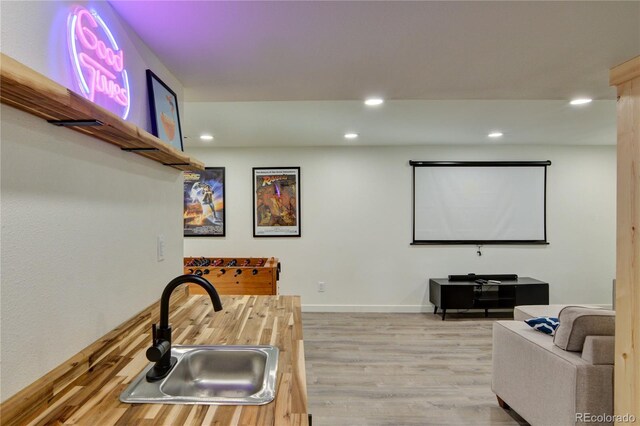 cinema room featuring light wood-type flooring and sink