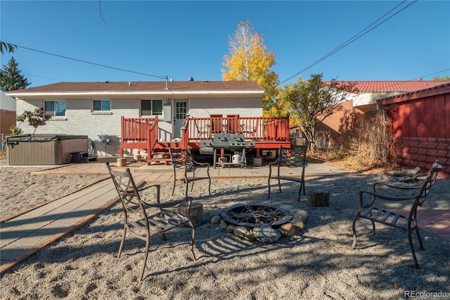 back of house with an outdoor fire pit, a wooden deck, and a hot tub