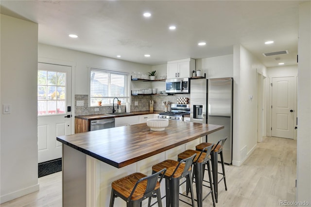 kitchen featuring a center island, white cabinets, sink, light hardwood / wood-style floors, and appliances with stainless steel finishes