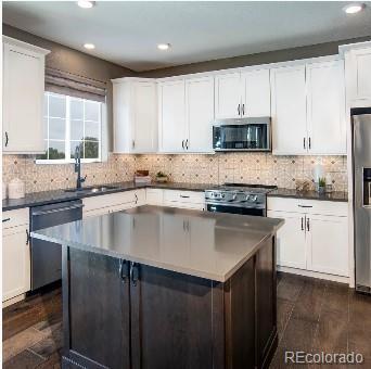 kitchen with sink, tasteful backsplash, dark hardwood / wood-style floors, white cabinets, and appliances with stainless steel finishes