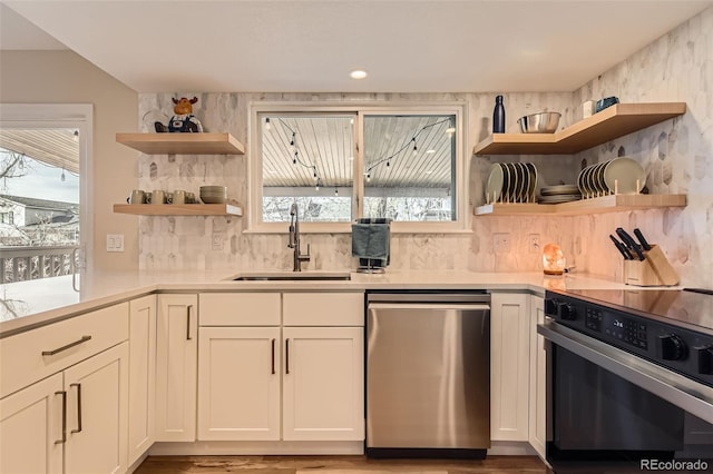 kitchen featuring range with electric cooktop, a sink, light countertops, open shelves, and stainless steel dishwasher