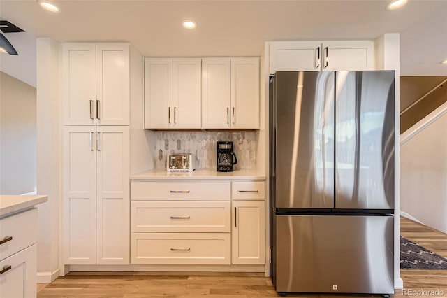 kitchen featuring light countertops, freestanding refrigerator, white cabinets, and light wood-style floors