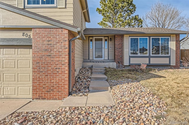 property entrance featuring an attached garage, roof with shingles, and brick siding