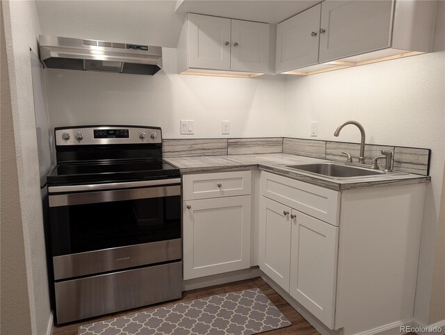 kitchen with dark wood-style floors, electric range, white cabinets, a sink, and under cabinet range hood