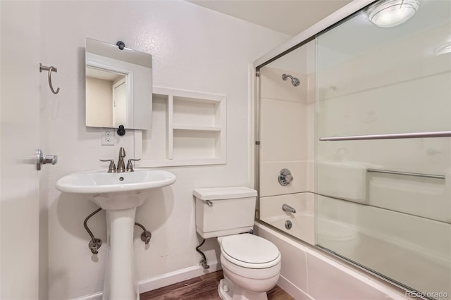 bathroom featuring baseboards, enclosed tub / shower combo, toilet, and wood finished floors