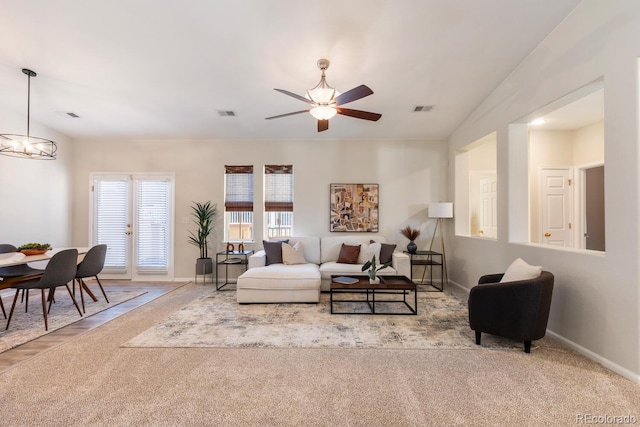 living room featuring light carpet and ceiling fan with notable chandelier