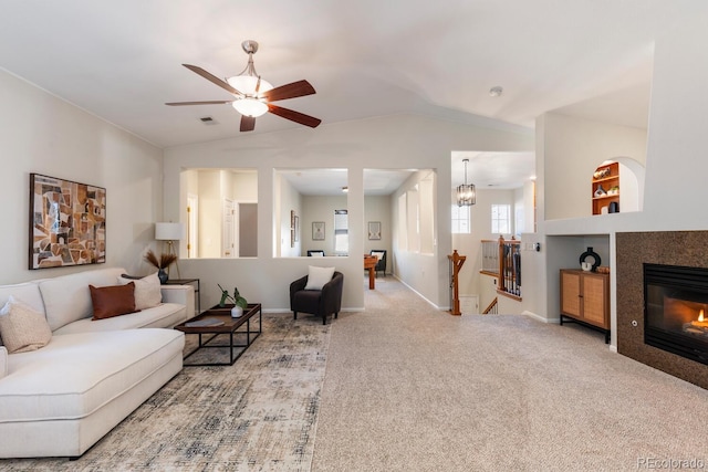 carpeted living room with ceiling fan with notable chandelier, lofted ceiling, a fireplace, and built in shelves