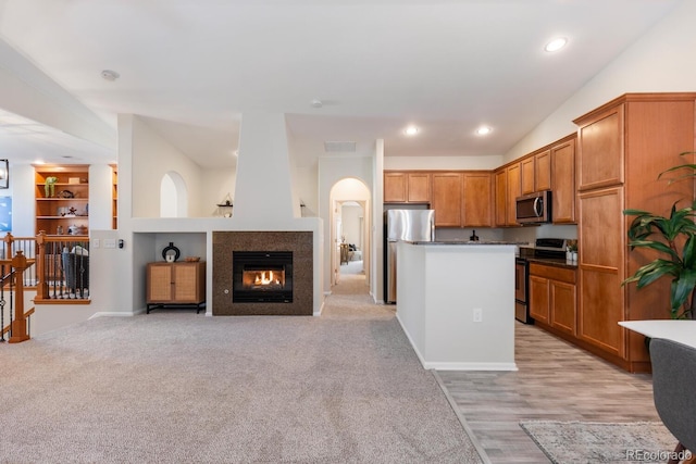 kitchen featuring built in shelves, appliances with stainless steel finishes, light carpet, and a kitchen island